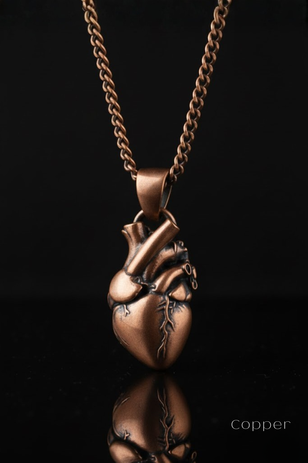 A copper-colored pendant necklace with a heart-shaped pendant is displayed against a black background.
