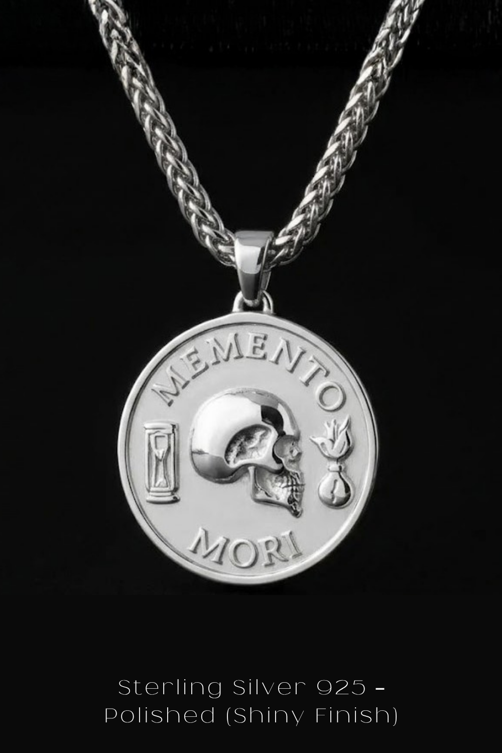 A silver pendant necklace with a circular medallion featuring a skull and the Latin phrase "Memento mori" (meaning remembrance of death ').