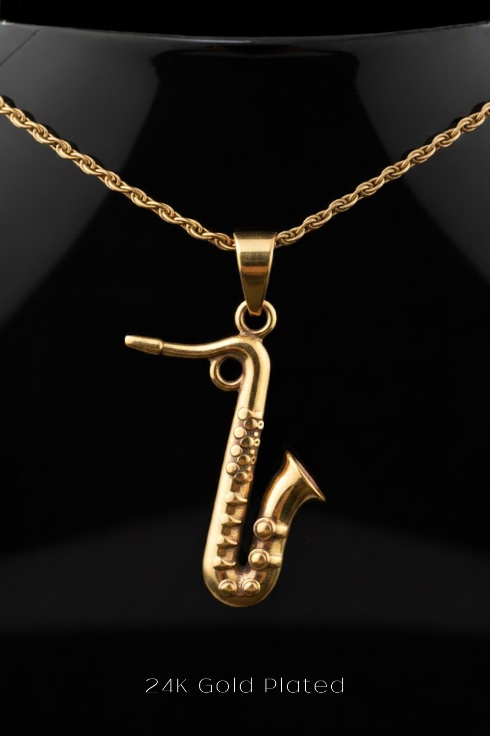 A gold-plated saxophone pendant is displayed against a black background.