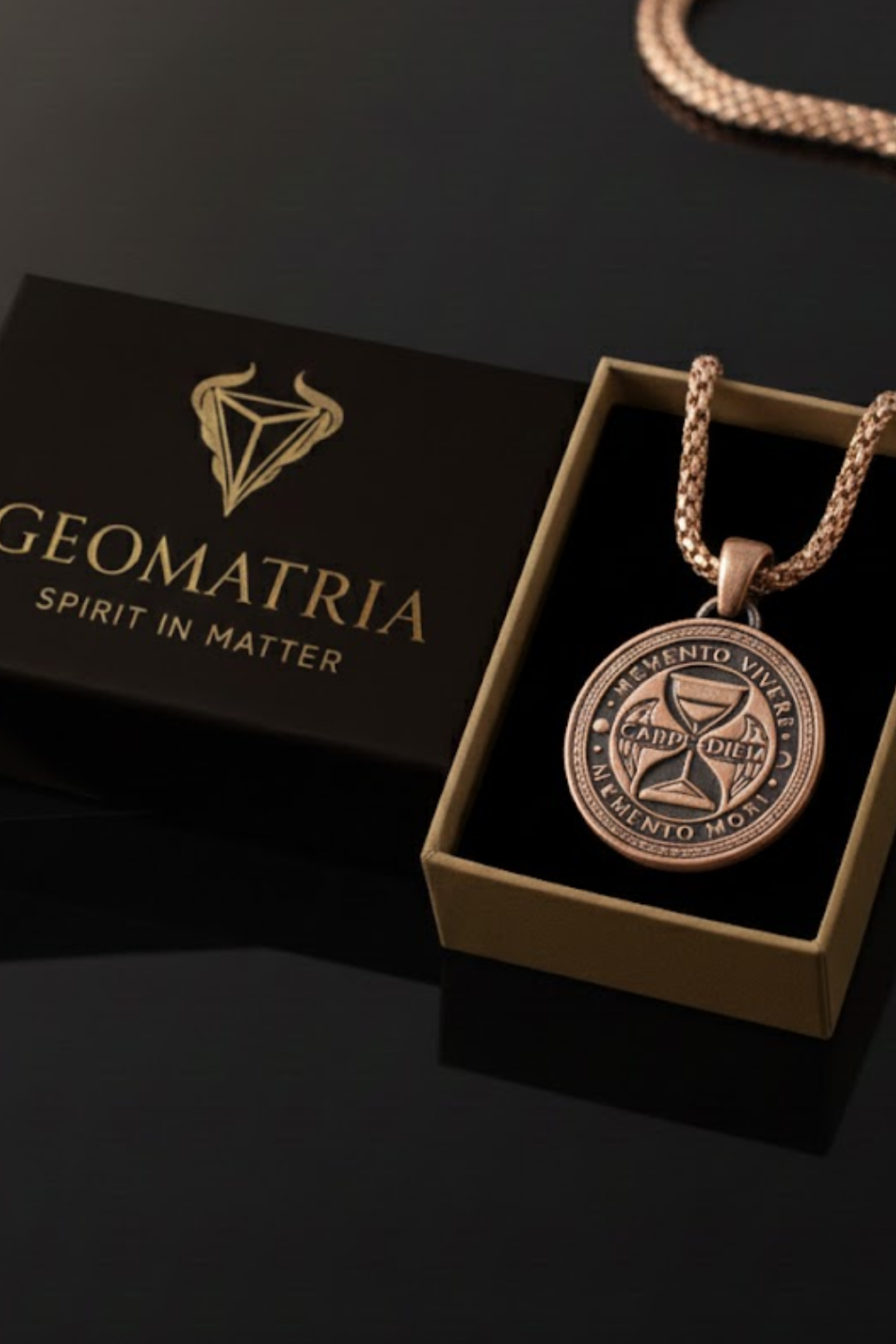 A pendant necklace with a circular pendant is displayed in a black box with the text "Geomatria SPIRIT IN MATER" written on it.