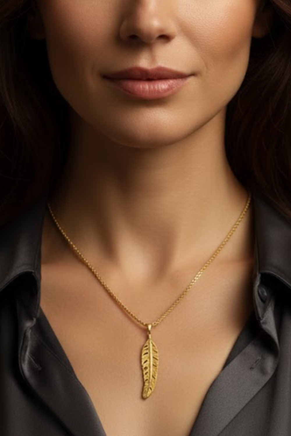 A close-up of a woman's neck and chest area, with a gold necklace featuring a leaf pendant.