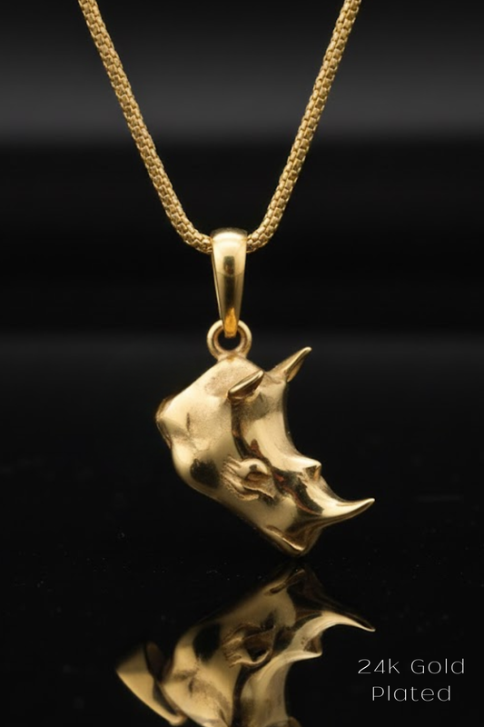A gold-colored pendant necklace with a unique, sculpted design is displayed against a black background.