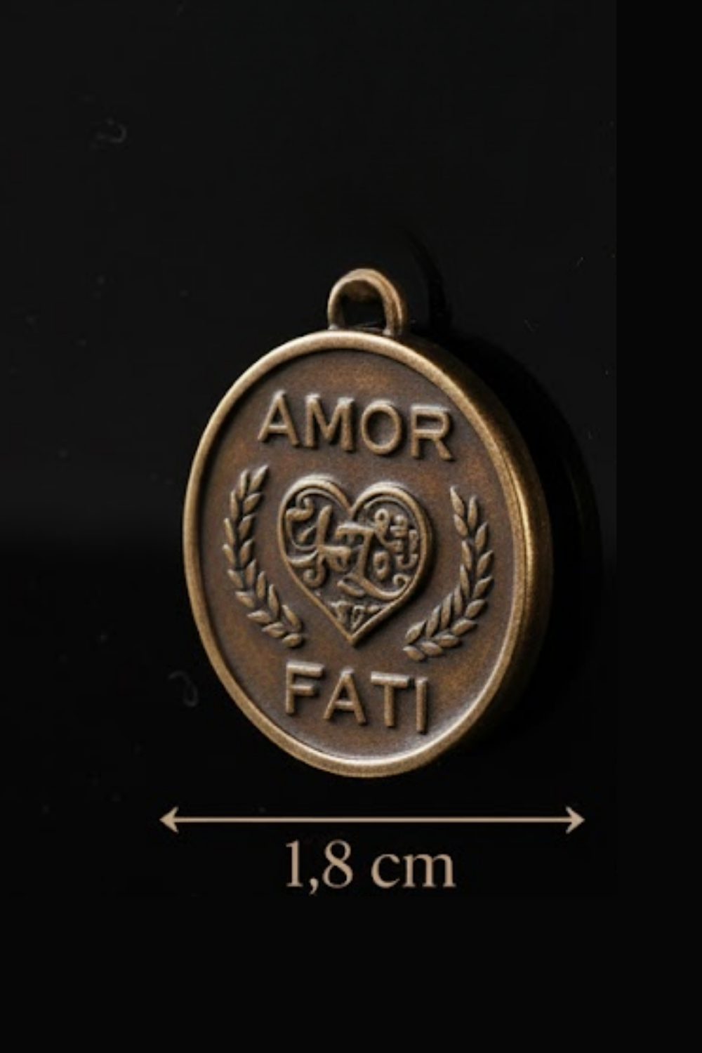 A close-up image of a round pendant with the words "Amor Fati" engraved on it, along with a heart symbol.