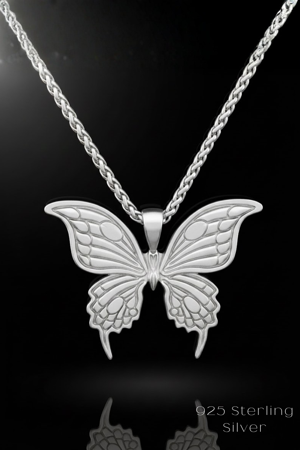 A silver butterfly pendant necklace against a black background.