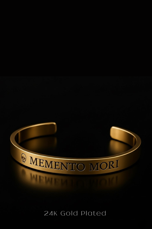 A 24k gold-plated bracelet with the engraved phrase "MEMENTO MORI" on it, set against a black background.