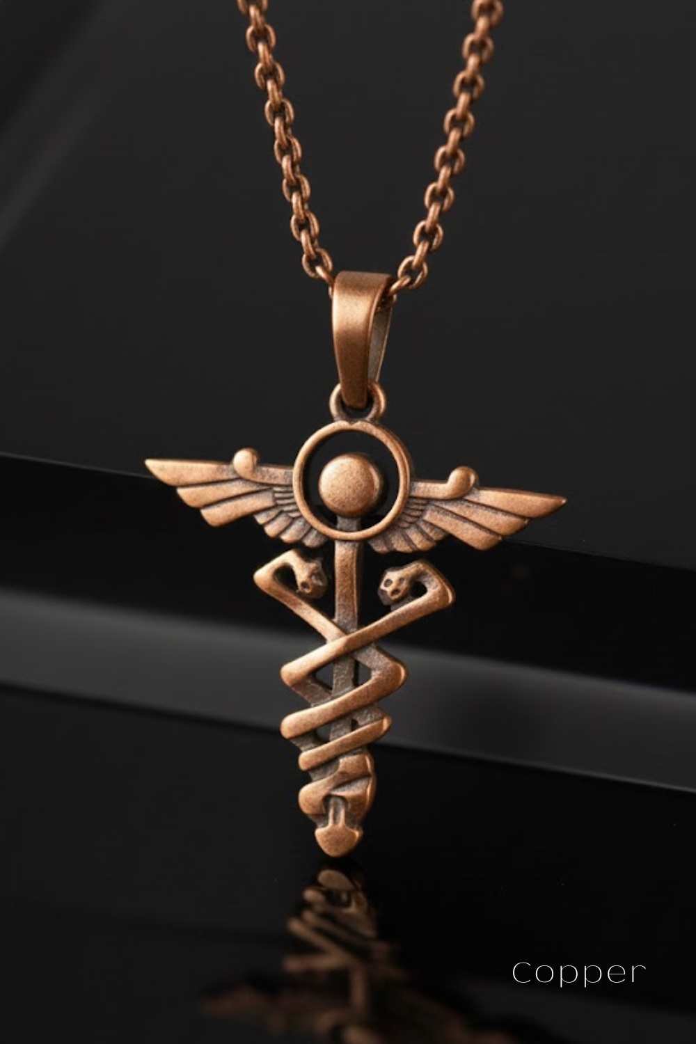 A copper-colored pendant necklace with a medical symbol, such as a crescent moon and cross, hanging from a chain.