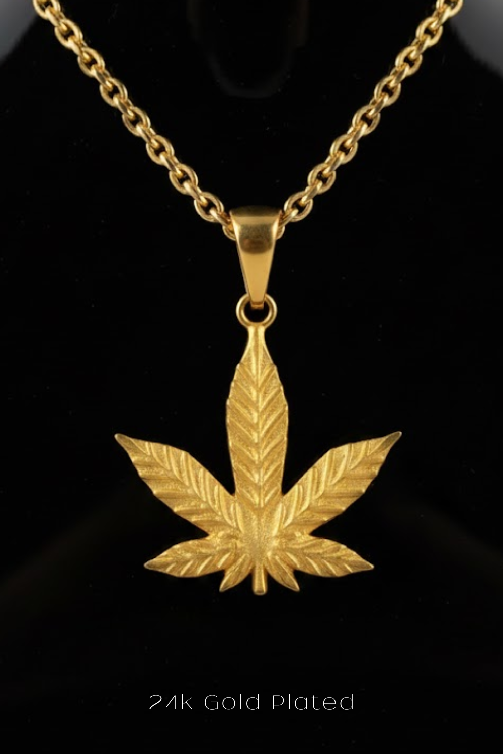 A 24k gold-plated pendant featuring a gold leaf design is displayed against a black background.