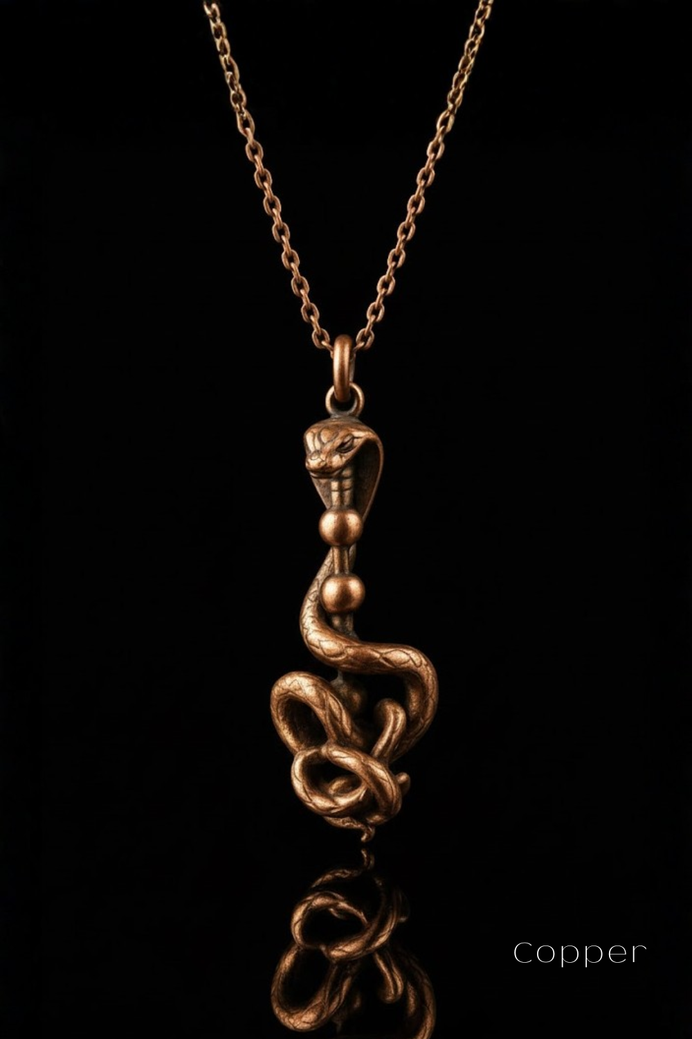 A copper-colored pendant necklace with a snake design, suspended from a chain against a black background.