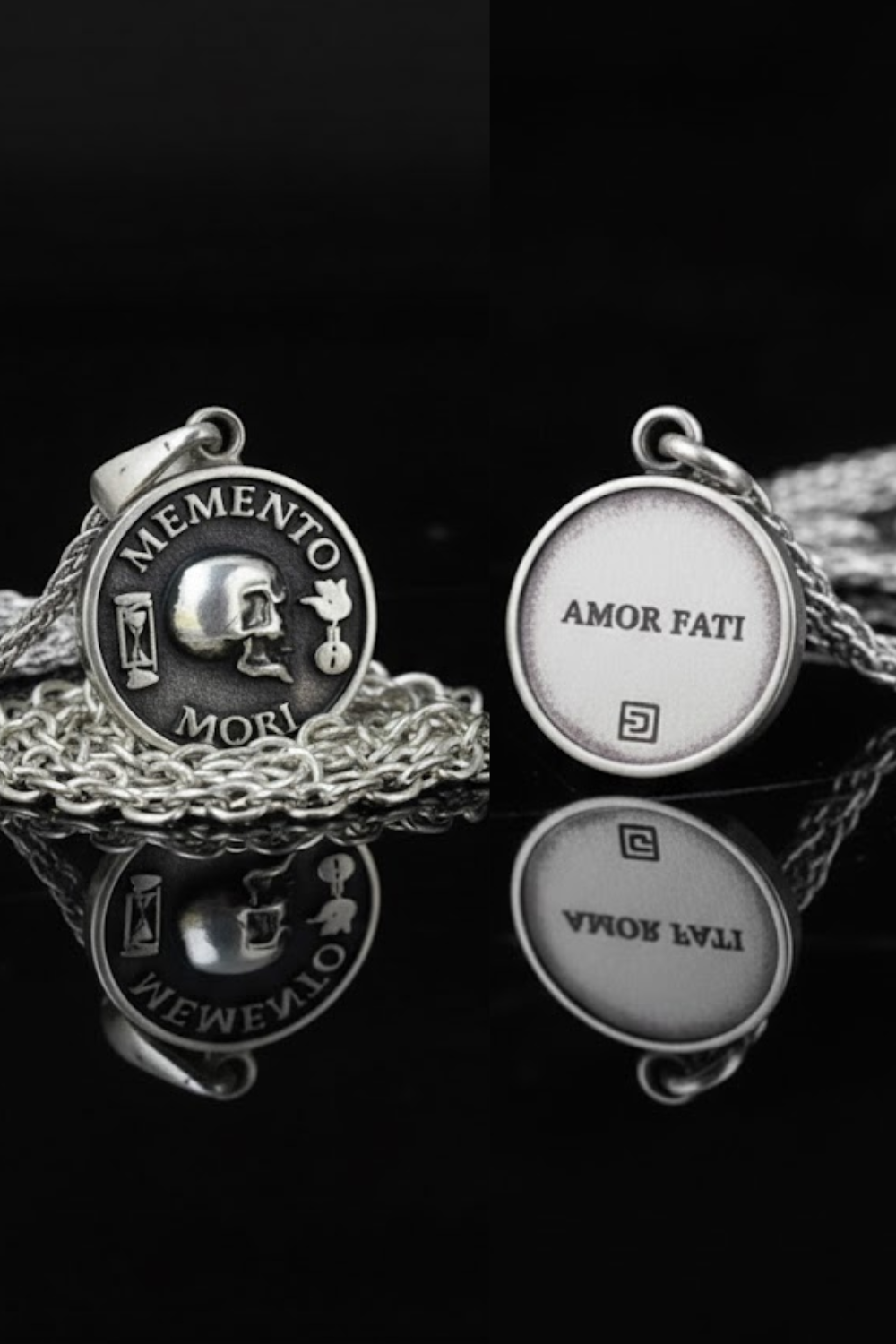 two silver pendants with the Latin motto "MEMENTO MORI" and "AMOR FATTI" engraved on them, displayed on a chain against a black background.