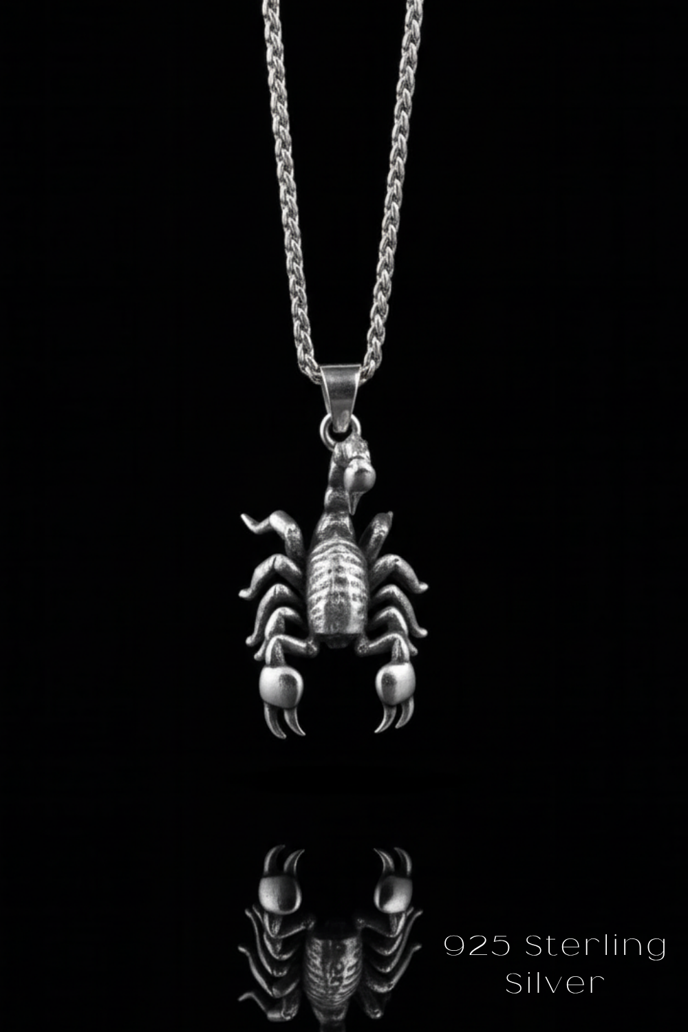 A silver-toned pendant necklace with a detailed design of a scorpion or spider-like creature, suspended from a chain against a black background.