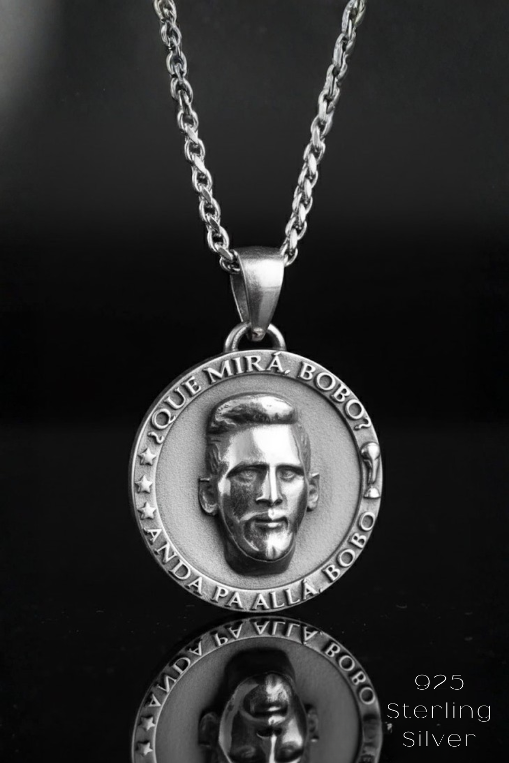 A silver pendant necklace with a circular medallion featuring a man's face.