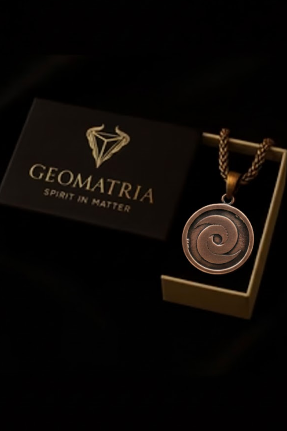 A pendant necklace with a circular pendant is displayed in a black box with the text "Geomatria" and "SPIRIT IN MATTERS" printed on it.