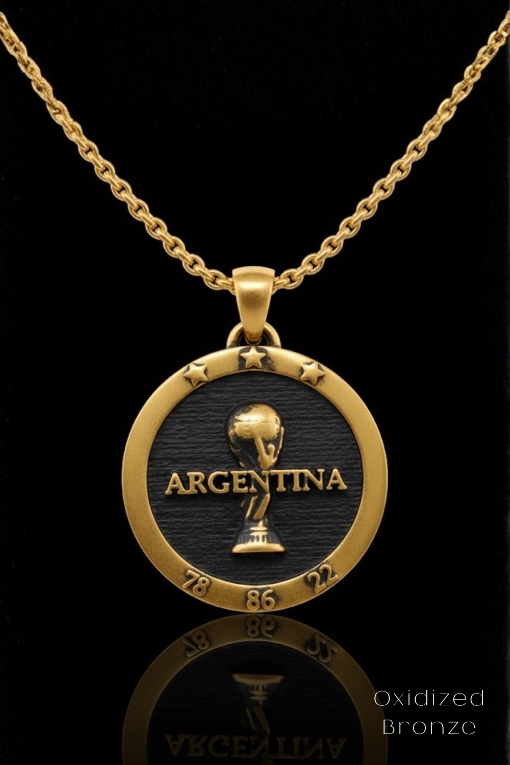 A gold-colored pendant necklace with a circular design featuring the word "ARGENTINA" and a trophy icon, set against a black background.