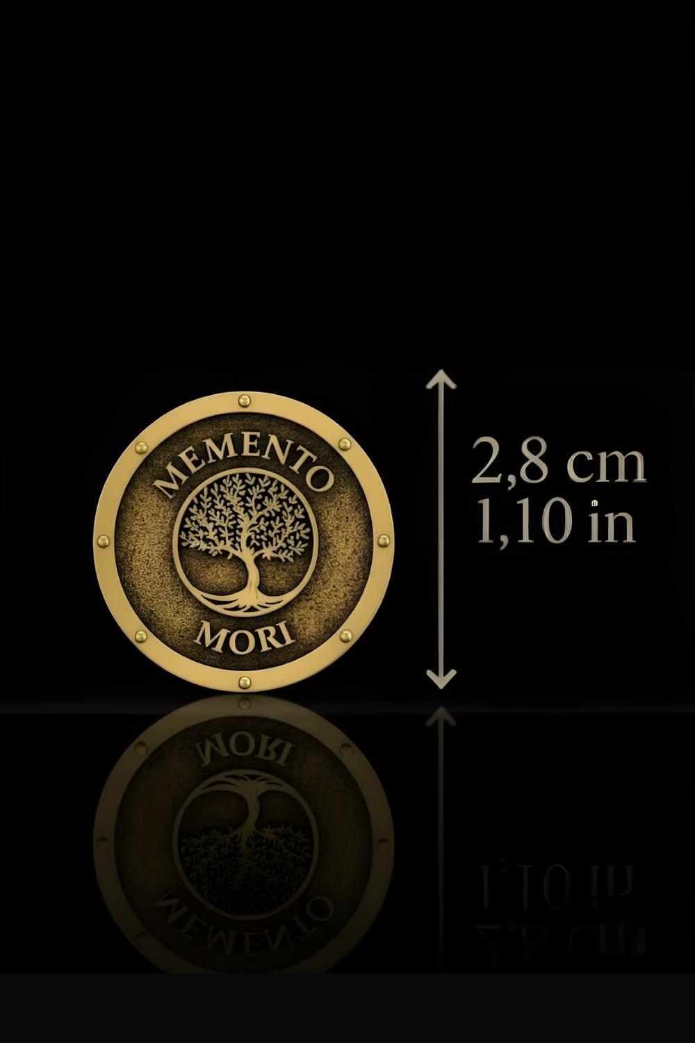 a gold-colored medallion with the text "MEMENTO MORI" on it, placed on a reflective surface. The medallion is approximately 2.8 cm in diameter, as indicated by the text "2,8 cm" next to it.