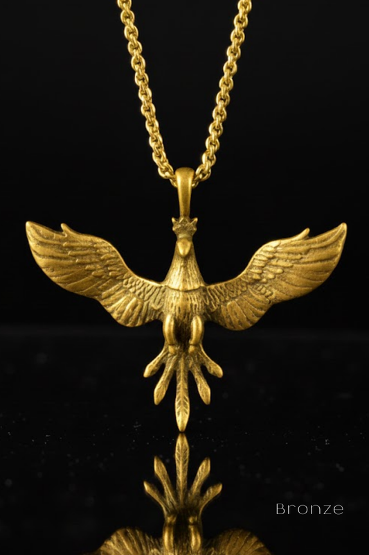 A gold-colored pendant in the shape of a bird, with wings spread wide, is displayed against a black background.