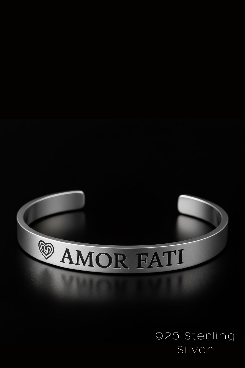 A silver bracelet with the text "Amor Fati" engraved on it, set against a black background.