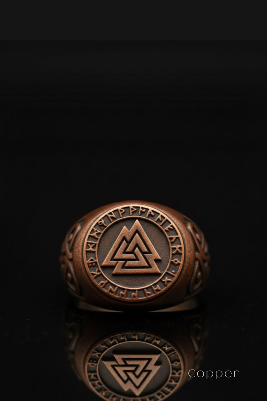 A copper ring with a circular design featuring a triangle and a symbol, placed on a reflective surface against a black background.