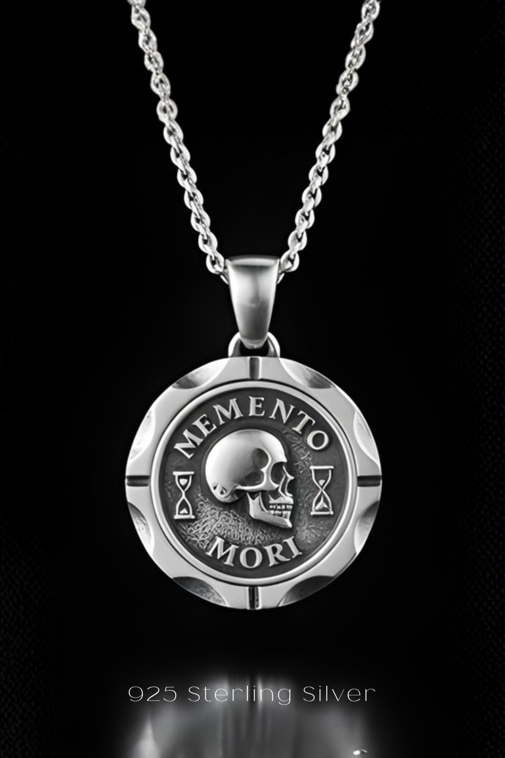 A silver necklace pendant with the Latin motto "MEMENTO MORI" engraved on it, which translates to "Life begins" or "Life ends".