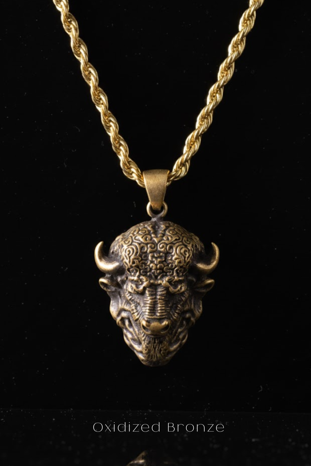 A gold-colored chain necklace with a pendant in the shape of a bull's head.