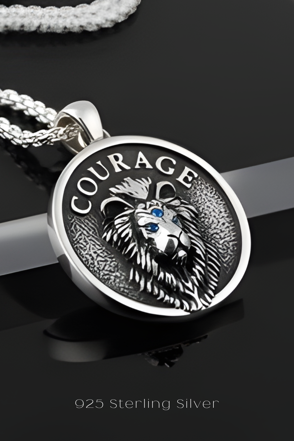 A silver pendant with a lion's head design and the word "COURAGE" engraved on it, along with a chain.