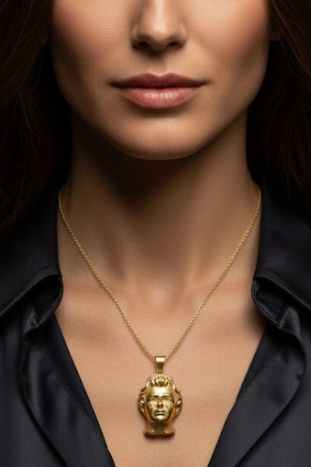 A close-up of a woman's neck and chest area, with a gold-colored pendant featuring a human head design hanging from a chain around her neck.