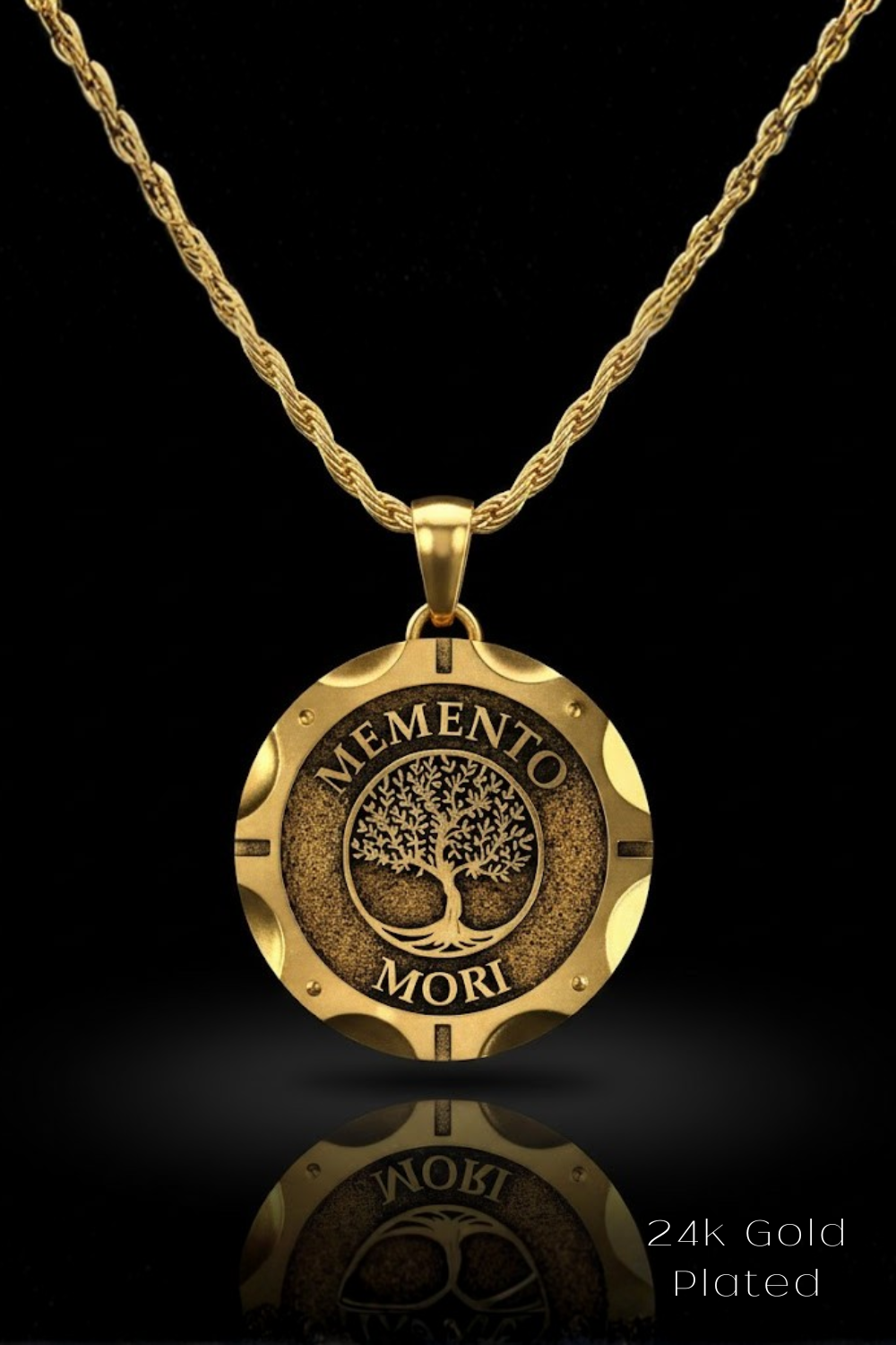 A 24k gold-plated pendant necklace with a circular medallion featuring the Latin motto "MEMENTO MORI" and a tree design.
