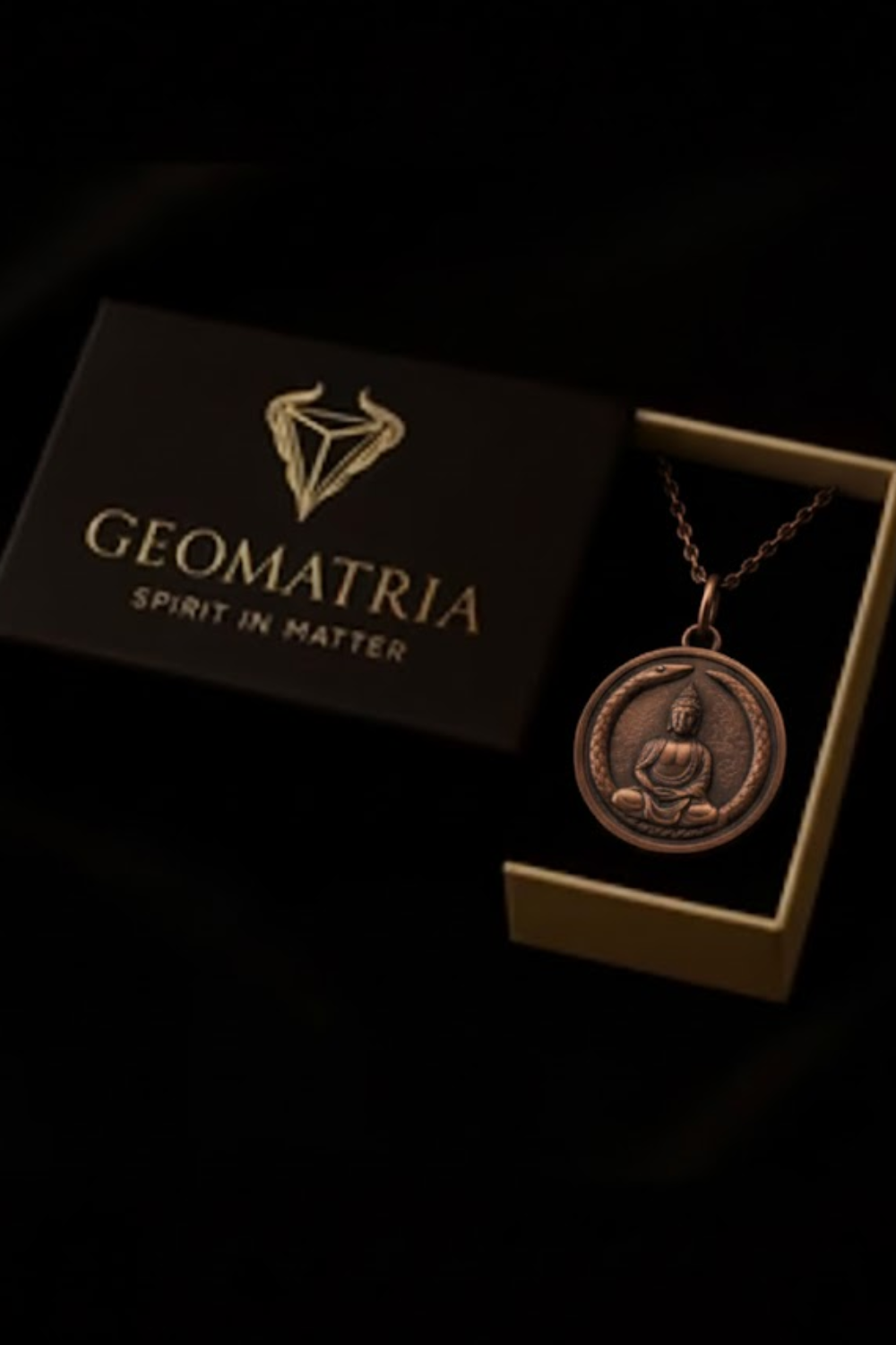 A pendant necklace with a circular medallion featuring a Buddha image, placed inside a black box with the word "Geomatria" printed on it.
