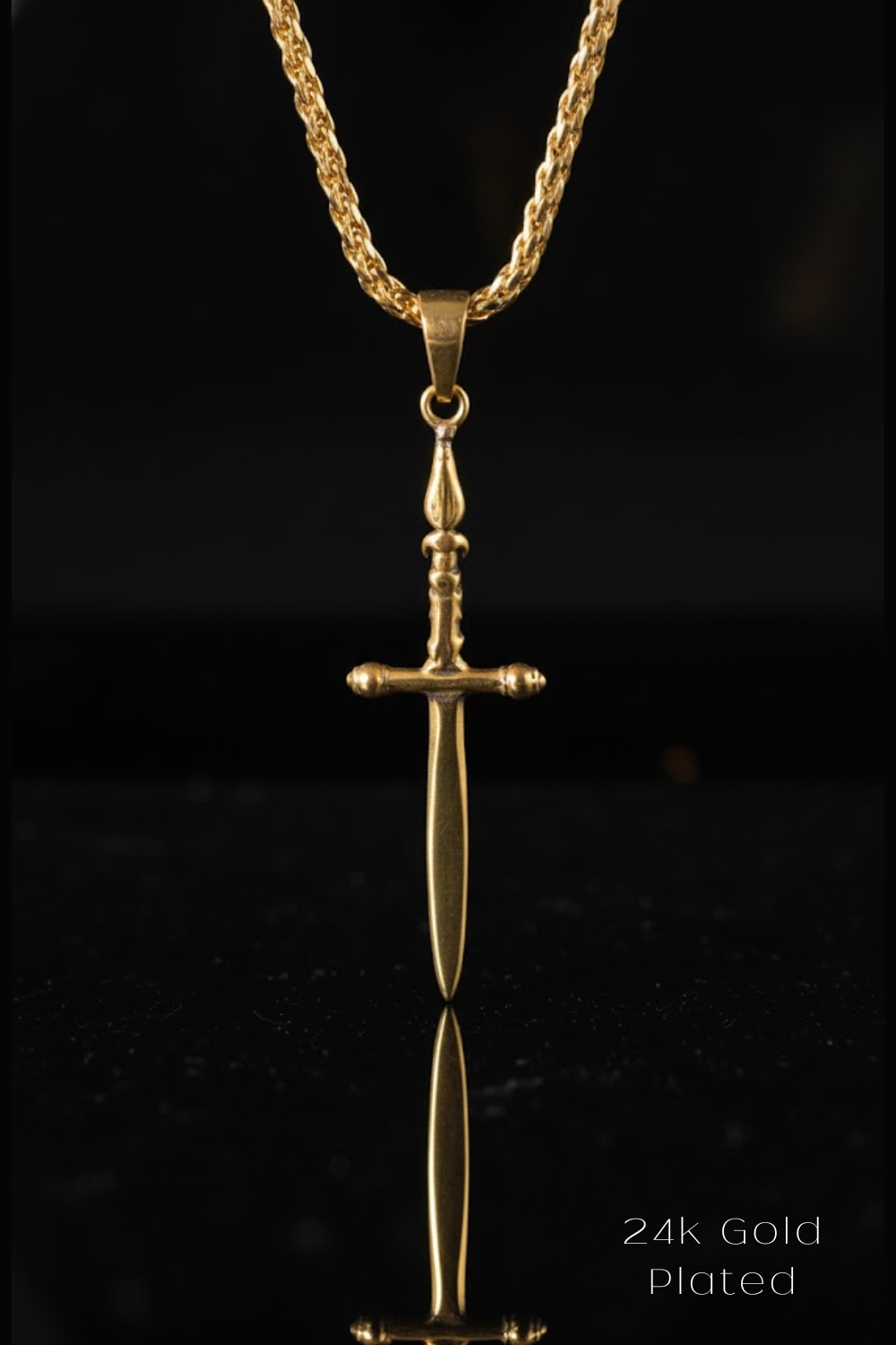 A 24k gold plated pendant in the shape of a sword is displayed against a black background.