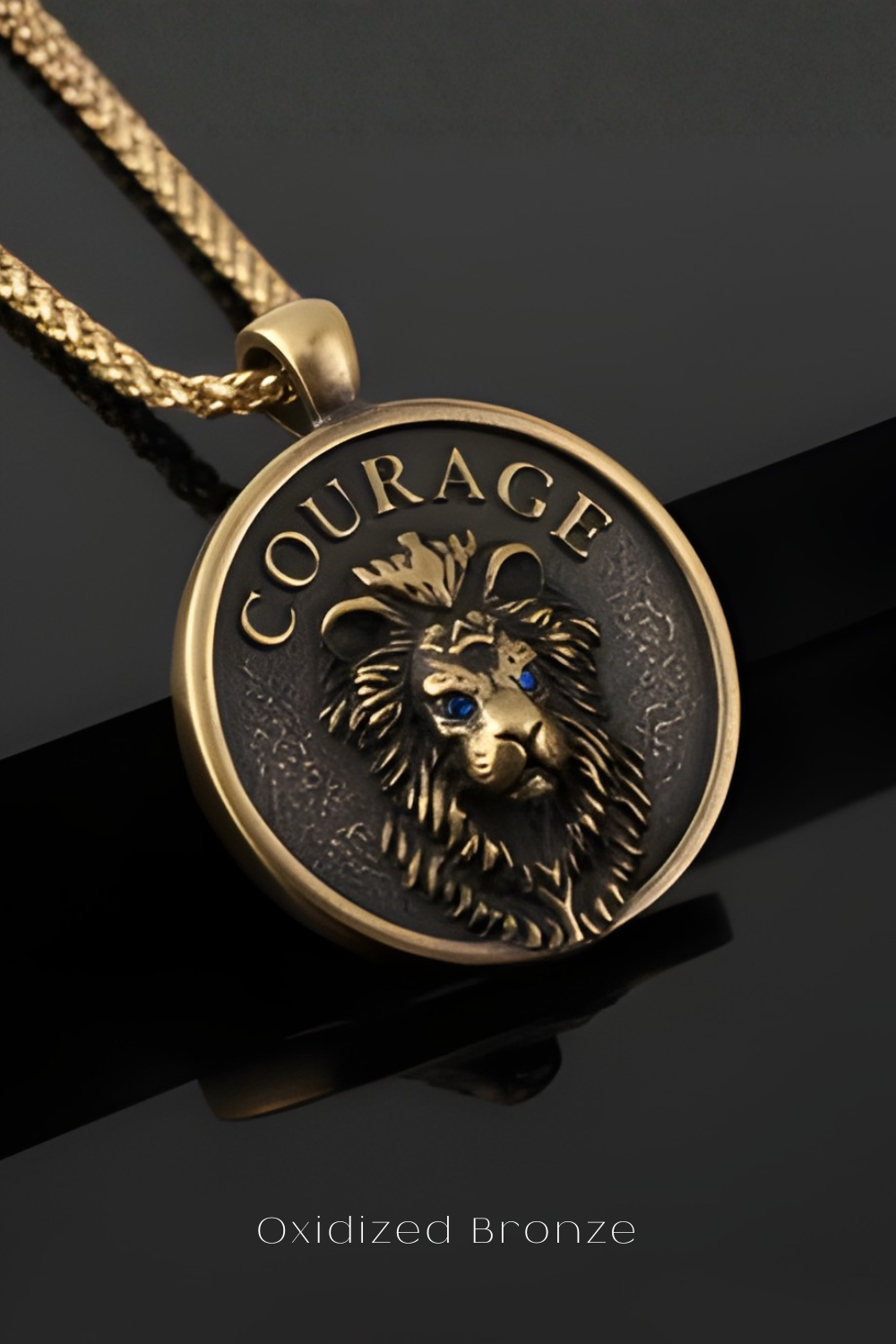 A close-up of a gold-colored pendant necklace with a circular medallion featuring a lion's head and the word "COURAGE" engraved on it.