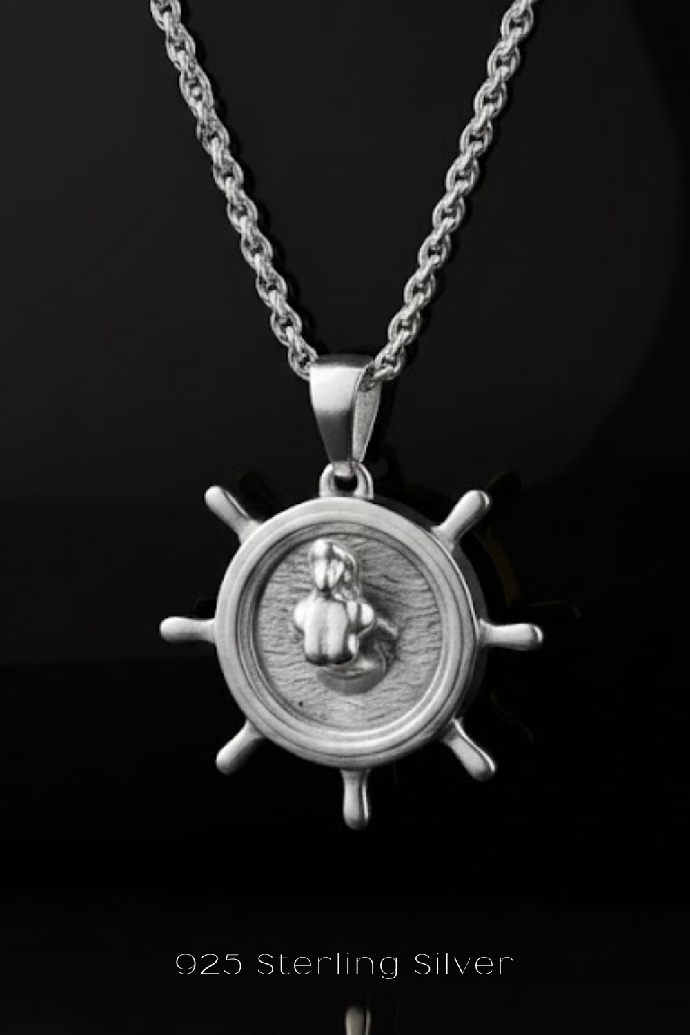 A silver-toned pendant necklace with a circular medallion featuring a mermaid design.