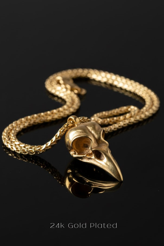 A gold-plated pendant in the shape of a bird's head is displayed on a gold chain against a black background.