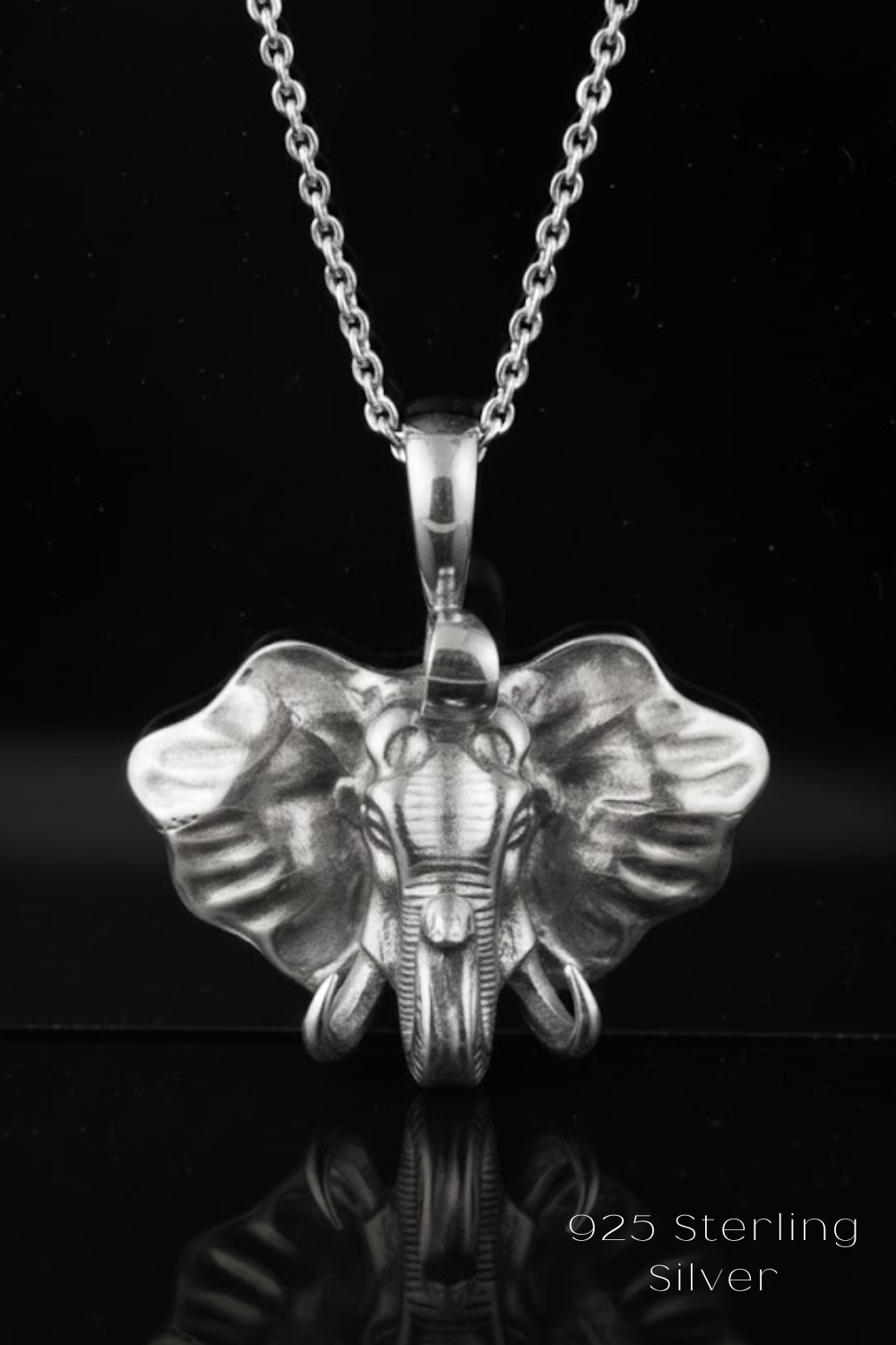 A silver elephant pendant necklace with a chain and a reflective surface below it.