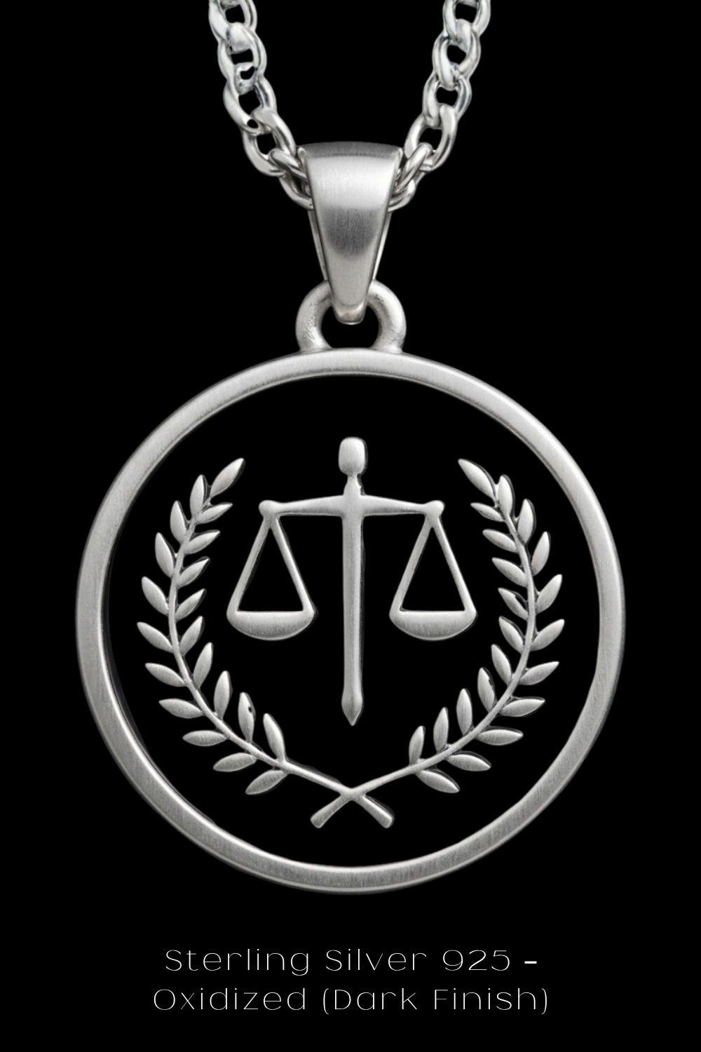A silver pendant necklace with a circular design featuring a scale of justice symbol and a laurel wreath.