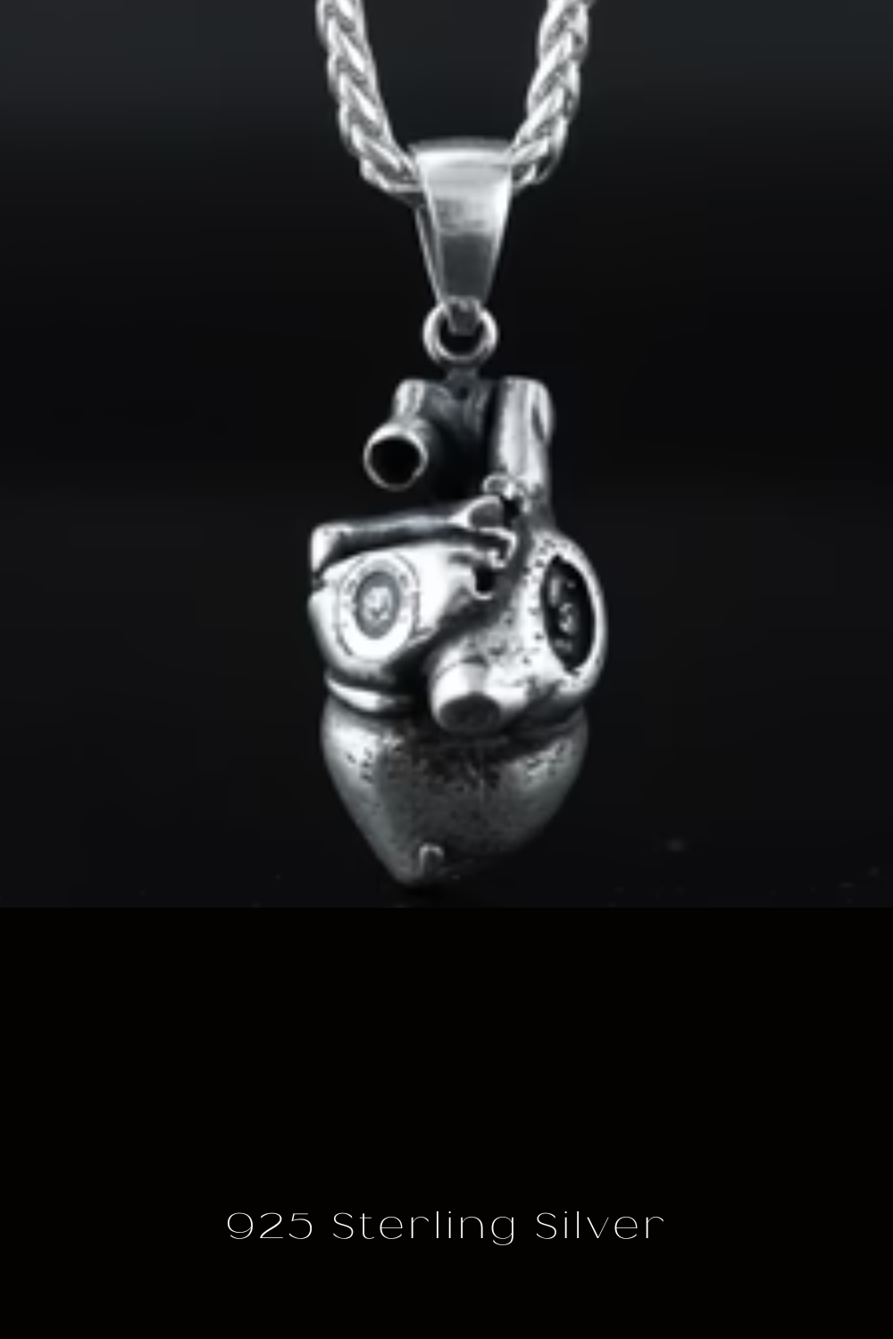 A silver heart-shaped pendant with a chain attached to it, displayed against a black background.