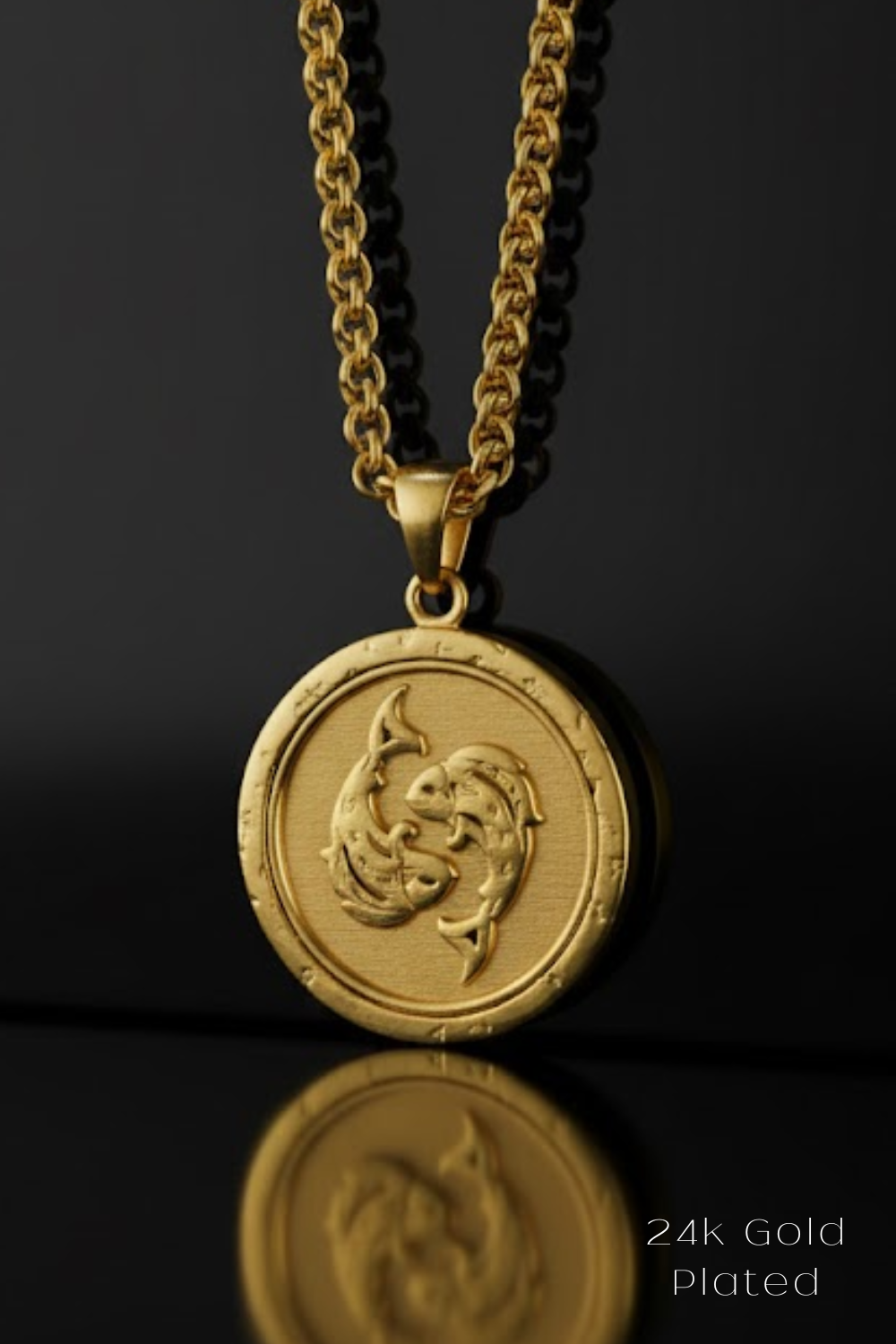 A gold-colored pendant necklace with a circular medallion featuring a fish design, suspended from a chain against a black background.