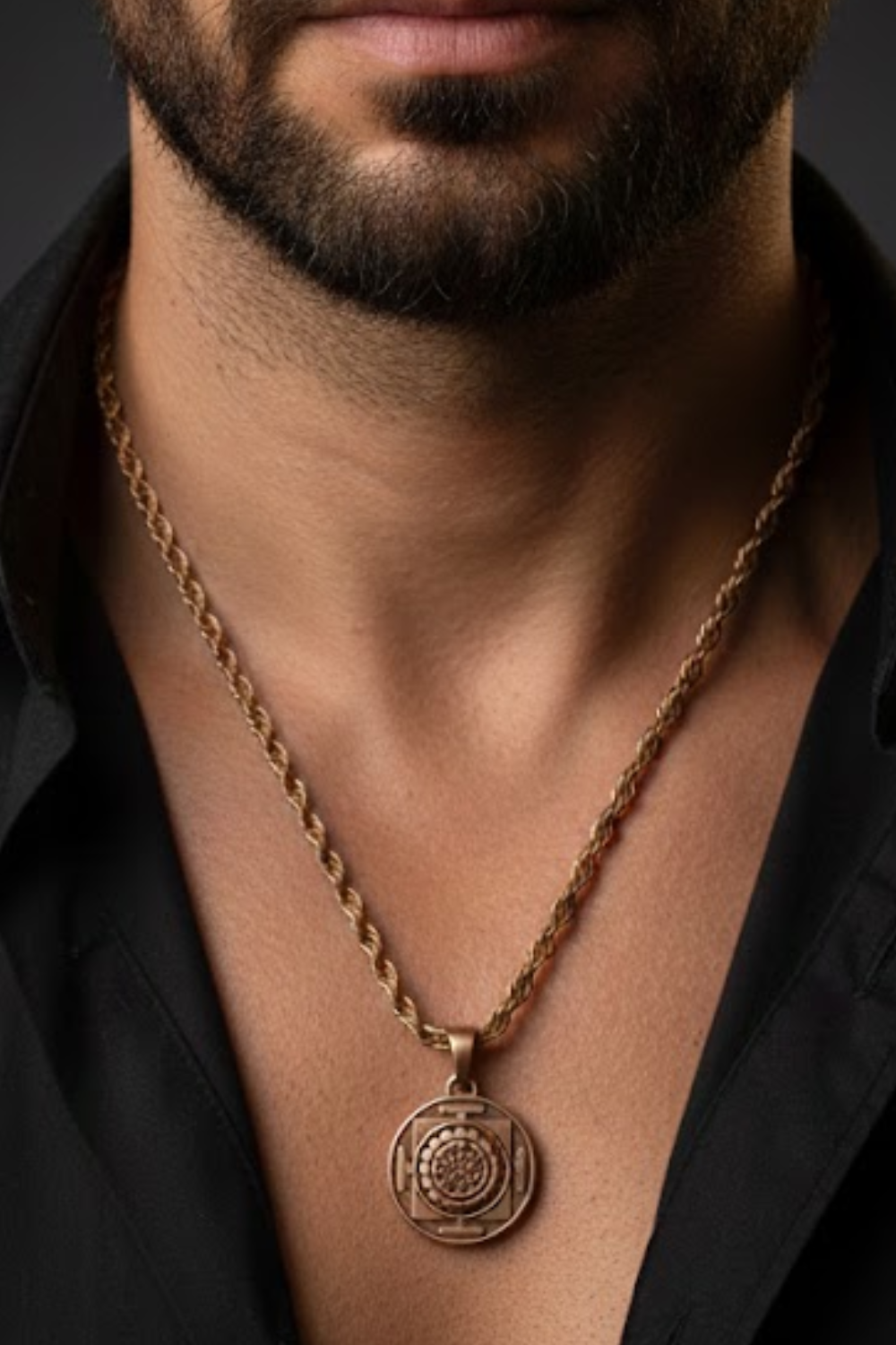 A close-up of a man's neck and chest area, with a gold-colored necklace featuring a pendant hanging from the neck.