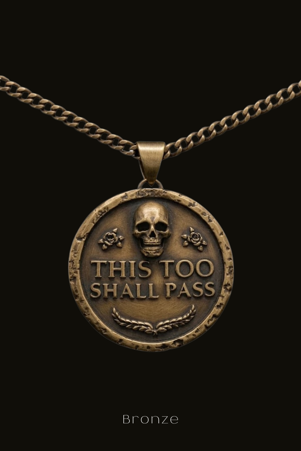 A bronze pendant with the text "THIS TOO SHALL PASS" and a skull design.