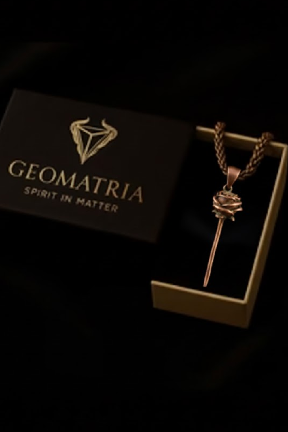 A necklace with a pendant is displayed in a black box with the text "Geomatria Spirit in Matter" printed on it.