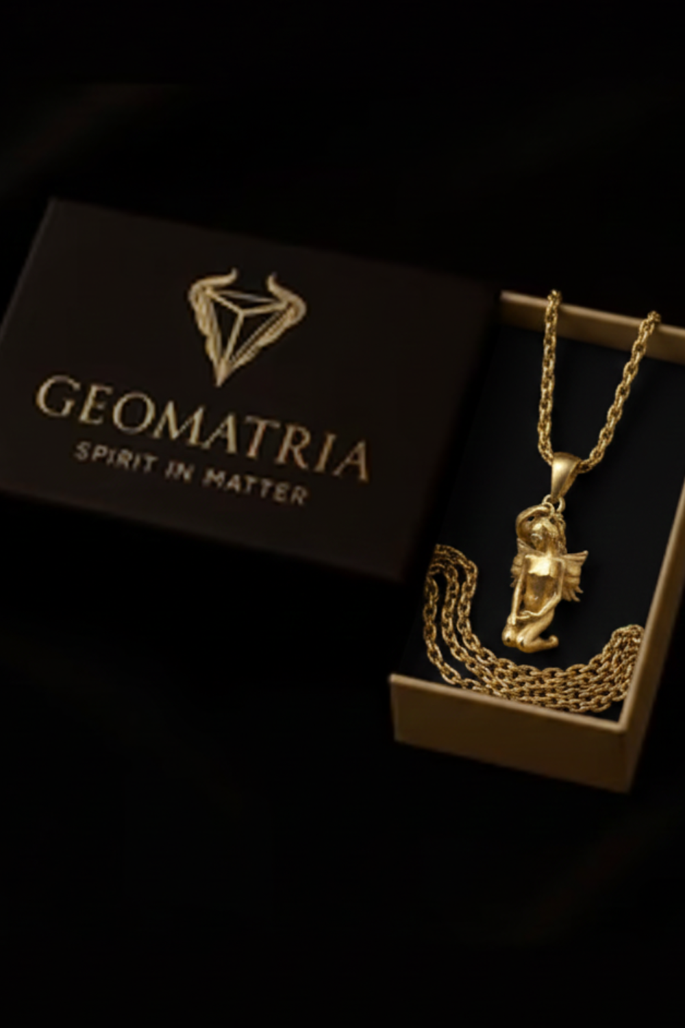 A gold necklace with a pendant is displayed in a box with the text "Geomatria" and "SPIRIT IN MATERIA" printed on it.
