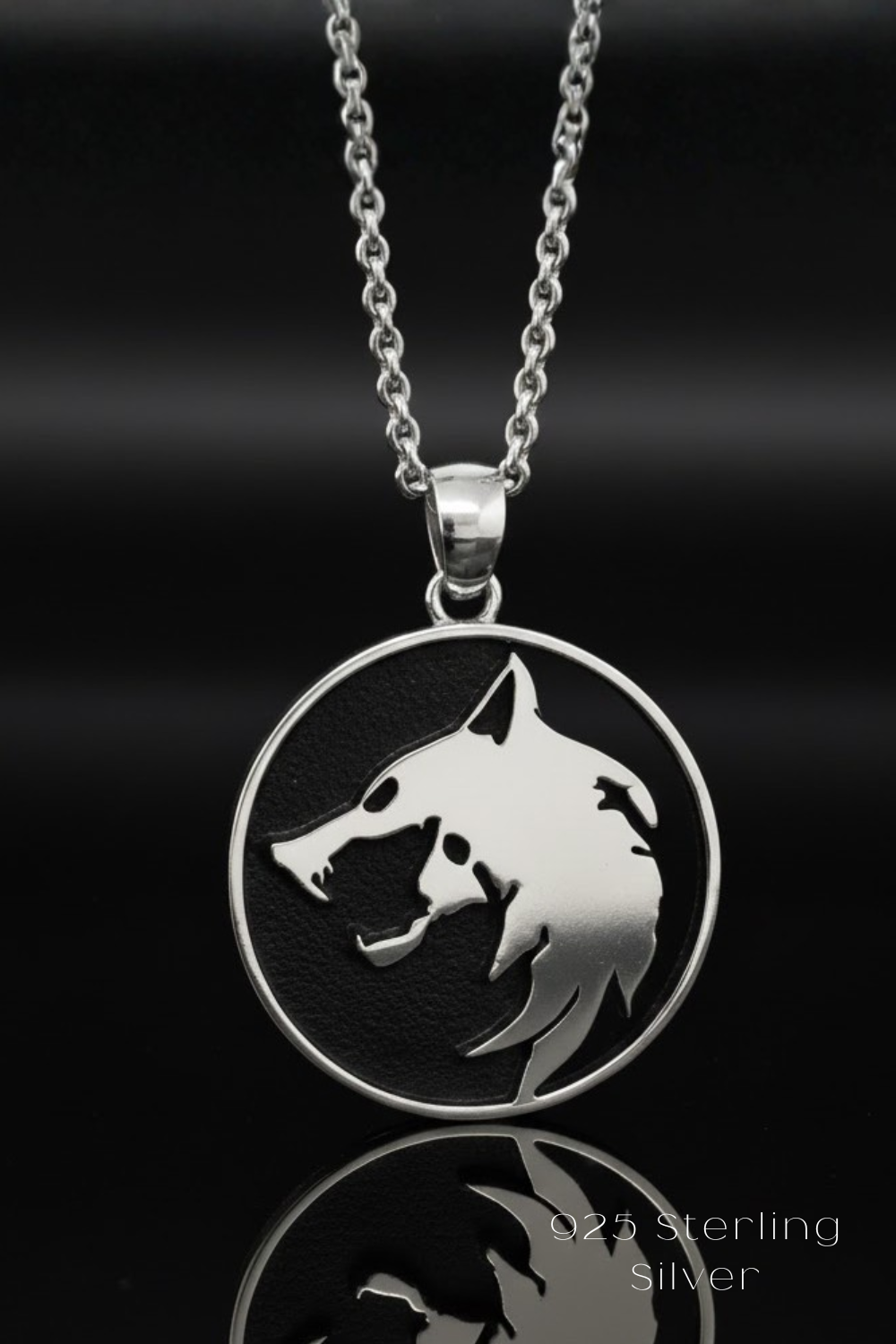 A silver pendant necklace with a circular pendant featuring a silhouette of a wolf's head.