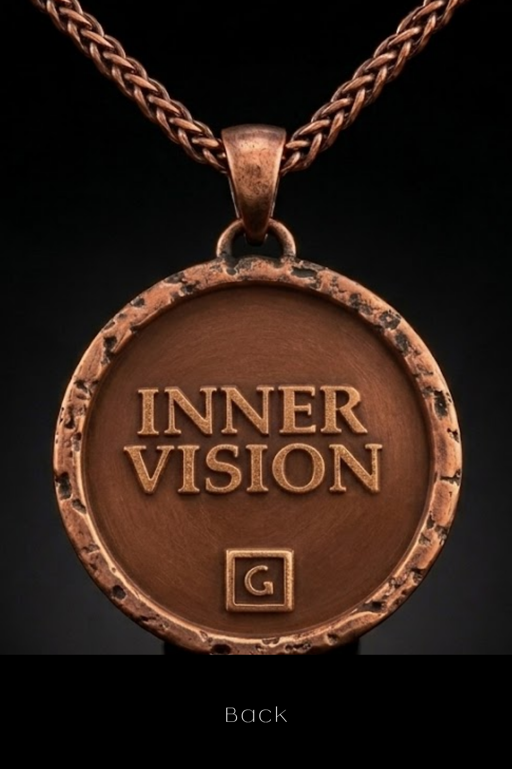 A close-up of a copper-colored pendant necklace with the text "INNER VISION" engraved on it.