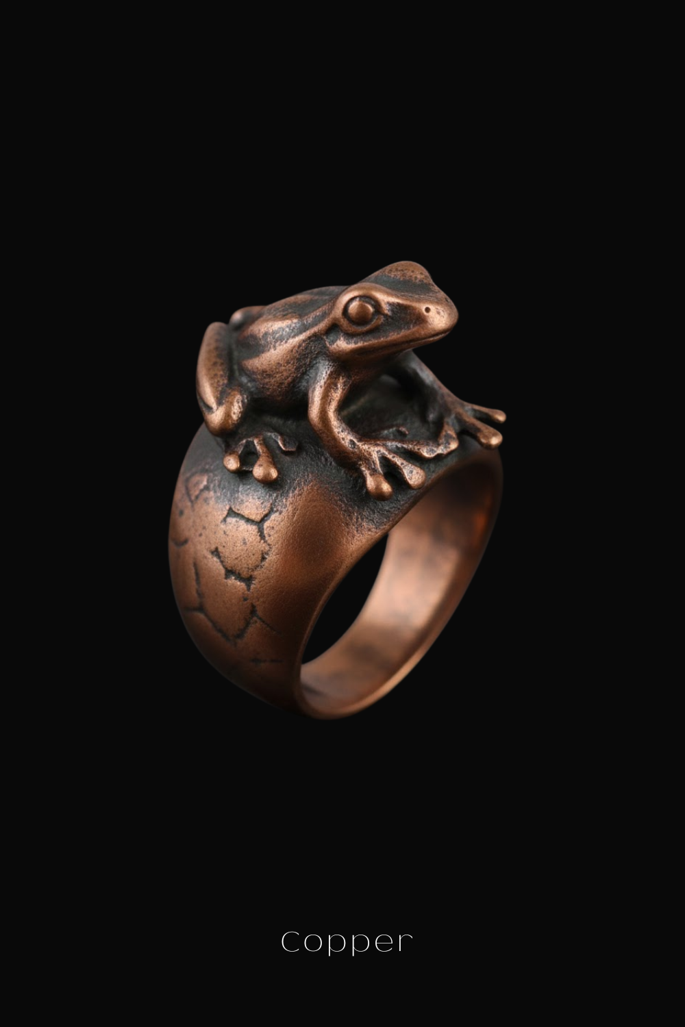 A copper ring featuring a detailed frog sculpture on top of a ring band against a black background.
