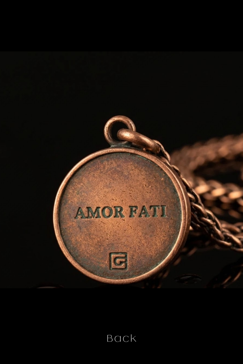 a close-up of a round, copper-colored pendant with the text "AMOR FATTI" engraved on it.