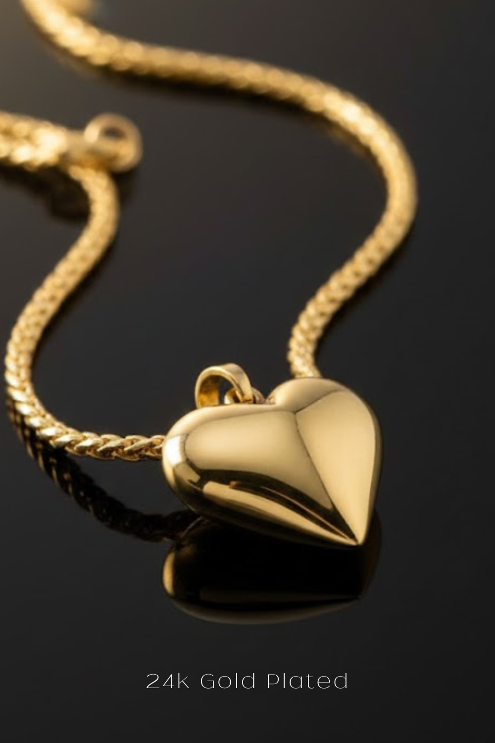 A 24k gold plated heart-shaped pendant necklace with a chain is displayed against a dark background.