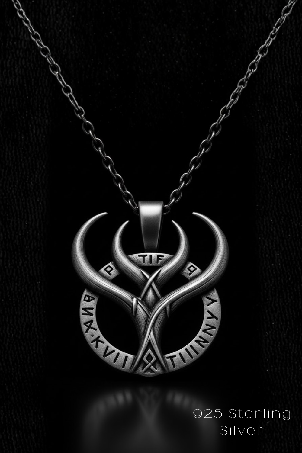 A silver necklace pendant with a unique design featuring a crescent moon and a symbol resembling a skull or skull-like shape.