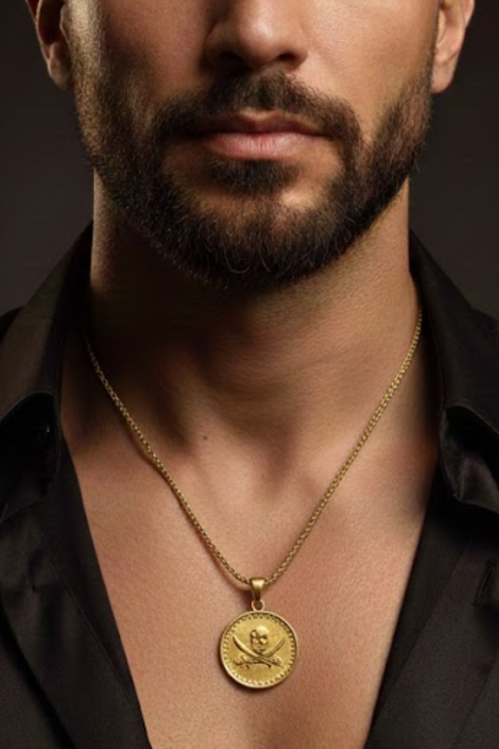 A close-up of a man's neck and chest area, with a gold-colored pendant necklace featuring a pirate-themed design.
