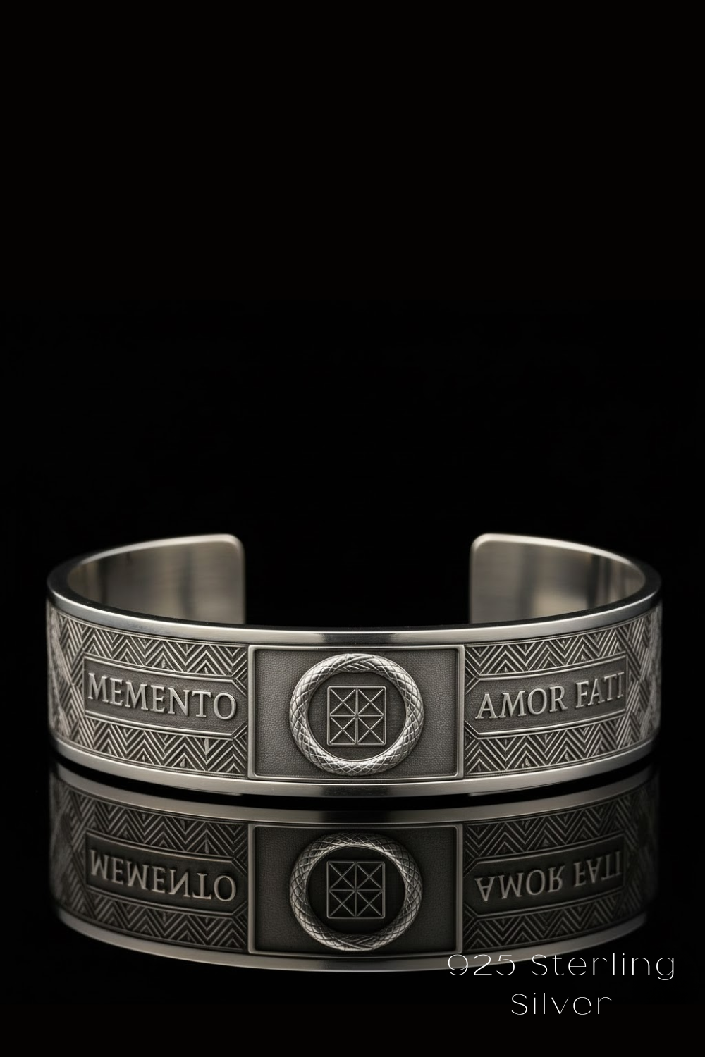 A silver cuff bracelet with the engraved phrases "MEMENTO" and "AMOR FATT" on the front, and a central circular design.