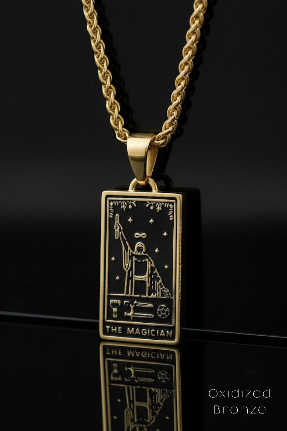 A gold-colored pendant necklace with a rectangular pendant featuring an illustration of a tarot card, specifically "The Magician".