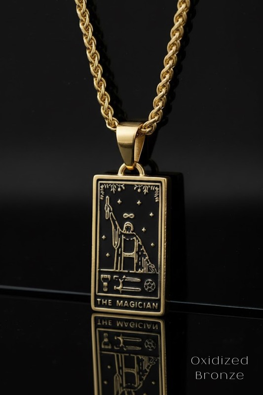 A gold-colored pendant necklace with a rectangular pendant featuring an illustration of a tarot card, specifically "The Magician".