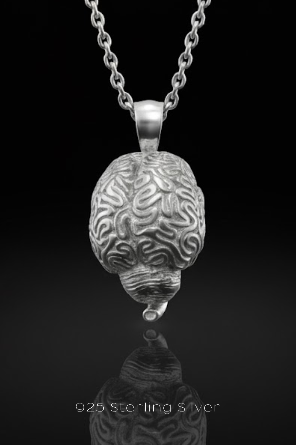 A silver-colored pendant necklace with a detailed brain design, suspended from a chain against a black background.